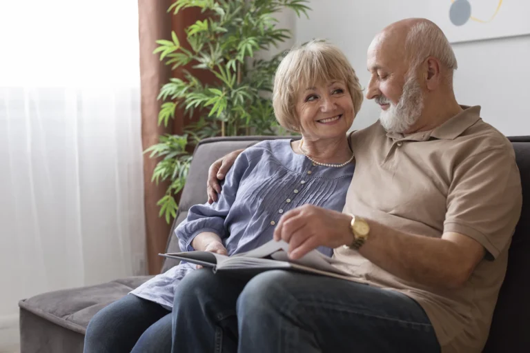 In the picture there is an elderly couple reading a magazine sitting on a sofa.